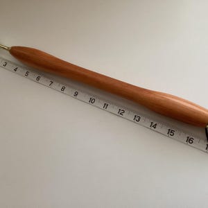 May include: A wooden back scratcher with a brass tip and a black cord. The scratcher is 43 cm long.