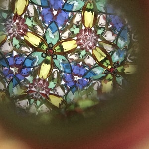 May include: A kaleidoscope image with a colorful, abstract pattern of flowers and geometric shapes. The image is dominated by shades of blue, green, yellow, and red.