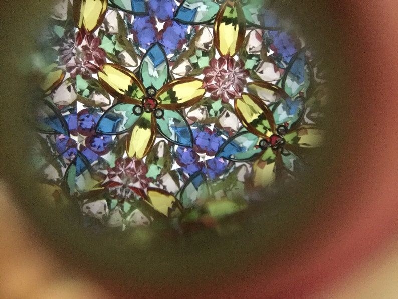 May include: A kaleidoscope image with a colorful, abstract pattern of flowers and geometric shapes. The image is dominated by shades of blue, green, yellow, and red.