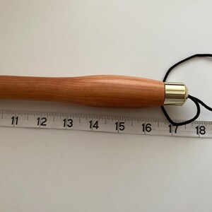 May include: A wooden knitting needle with a gold-coloured tip and a black cord loop. The needle is 17 inches (43 cm) long.
