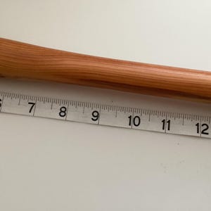 May include: A close-up of a wooden dowel rod measuring 13 inches in length. The rod is light brown in colour and has a smooth, polished finish.
