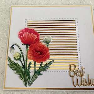 May include: A white greeting card with gold detailing. It features a floral design with red poppies and green leaves. The words "Best Wishes" are in gold script. The card is square in shape.