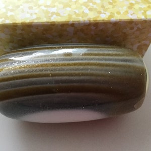 May include: A gold and silver striped cylindrical bottle stopper with a gold rim.