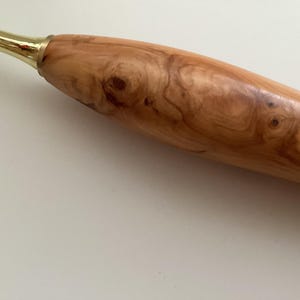 May include: A wooden rolling pin with a natural wood grain pattern and a brass handle.
