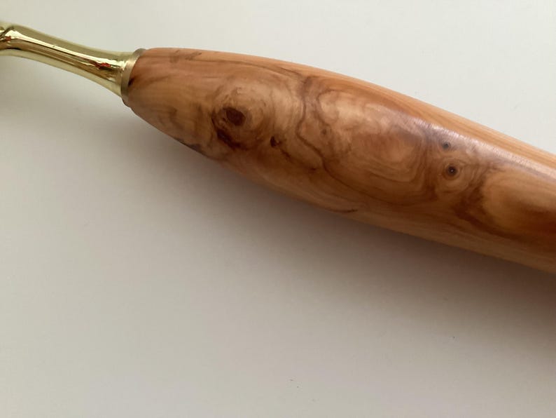 May include: A wooden rolling pin with a natural wood grain pattern and a brass handle.