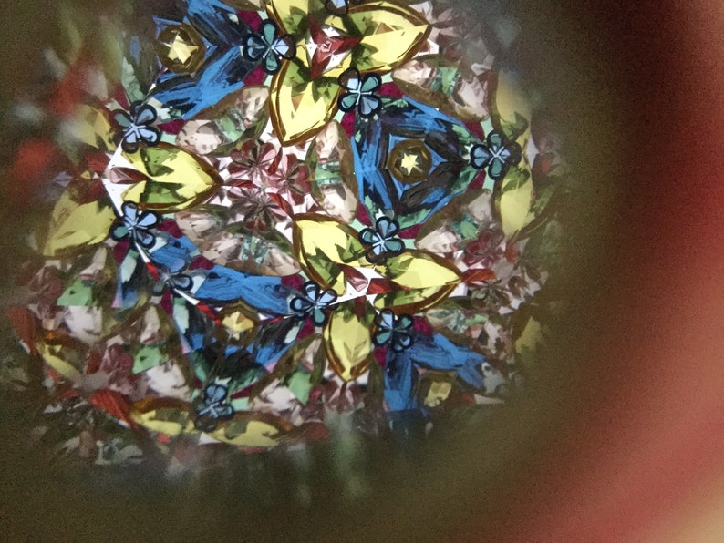 May include: A kaleidoscope image with a symmetrical pattern of blue, yellow, green, and red shapes. The image is created by reflecting light through a series of mirrors.