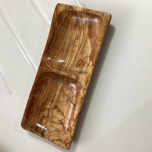 May include: A rectangular olive wood serving tray with two divided sections. The tray has a natural wood finish and is ideal for serving snacks, appetisers, or dips.