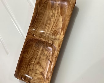 May include: A rectangular olive wood serving tray with two divided sections. The tray has a natural wood finish and is perfect for serving snacks, appetizers, or dips.