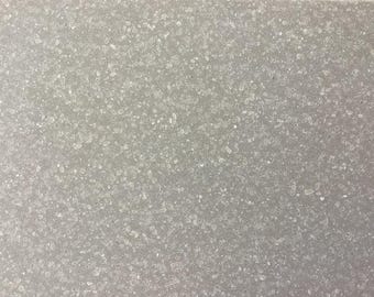 May include: A close-up of a textured, gray surface with a fine, white, granular pattern.