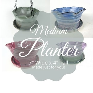 May include: Four ceramic hanging planters in different colors, including green, blue, purple, and red. Each planter has a ruffled rim and a matching saucer. The planters are 7 inches wide and 4 inches tall. The text "Medium Planter 7" Wide x 4" Tall Made just for you!" is displayed on the image.
