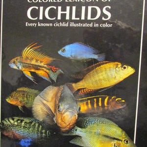 May include: A book cover featuring the title "THE MOST COMPLETE COLORED LEXICON OF CICHLIDS" with various colorful cichlid fish illustrations. The text "Every known cichlid illustrated in color" is also present. The author's name, Dr. Herbert R. Axelrod, is at the bottom.