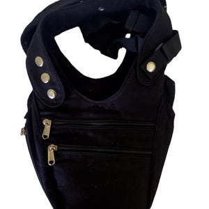 May include: Black crossbody bag with multiple zippered compartments and adjustable strap. The bag features silver-toned hardware, including zippers and decorative studs. The design includes a curved shape and a comfortable shoulder strap.