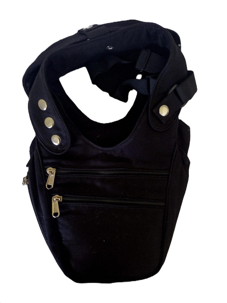 May include: Black crossbody bag with multiple zippered compartments and adjustable strap. The bag features silver-toned hardware, including zippers and decorative studs. The design includes a curved shape and a comfortable shoulder strap.