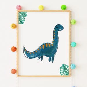 Puede incluir: Una impresión en acuarela enmarcada de un dinosaurio azul con rayas naranjas. El dinosaurio tiene un cuello y una cola largos. La impresión está en un marco de madera clara. Pompones coloridos y acentos de hojas verdes decoran la pared blanca.