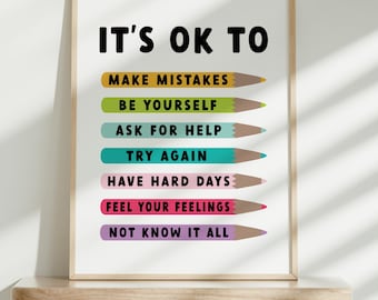 Op de afbeelding: Een ingelijst print met de tekst "It's OK to" en een lijst met zinnen, waaronder "Make Mistakes", "Be Yourself", "Ask for Help", "Try Again", "Have Hard Days", "Feel Your Feelings" en "Not Know It All". Elke zin staat op een kleurrijke potloodvormige afbeelding.