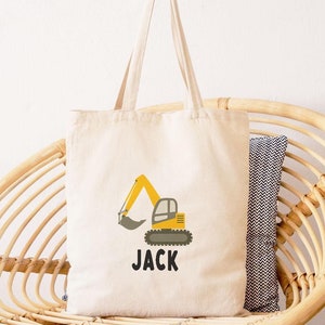 May include: A white canvas tote bag with a yellow excavator design and the name "JACK" printed in black.