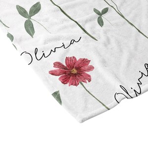 May include: White fleece blanket with a floral pattern and the name Olivia written twice in cursive.