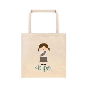 May include: A beige tote bag featuring a brown girl guide character and the name "Harper" in teal text.