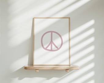Op de afbeelding: Een ingelijst print met een roze vredesteken op een witte achtergrond. De print staat op een houten plank.