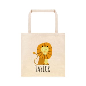 May include: A beige tote bag with a lion illustration and the name "TAYLOR" printed in black.