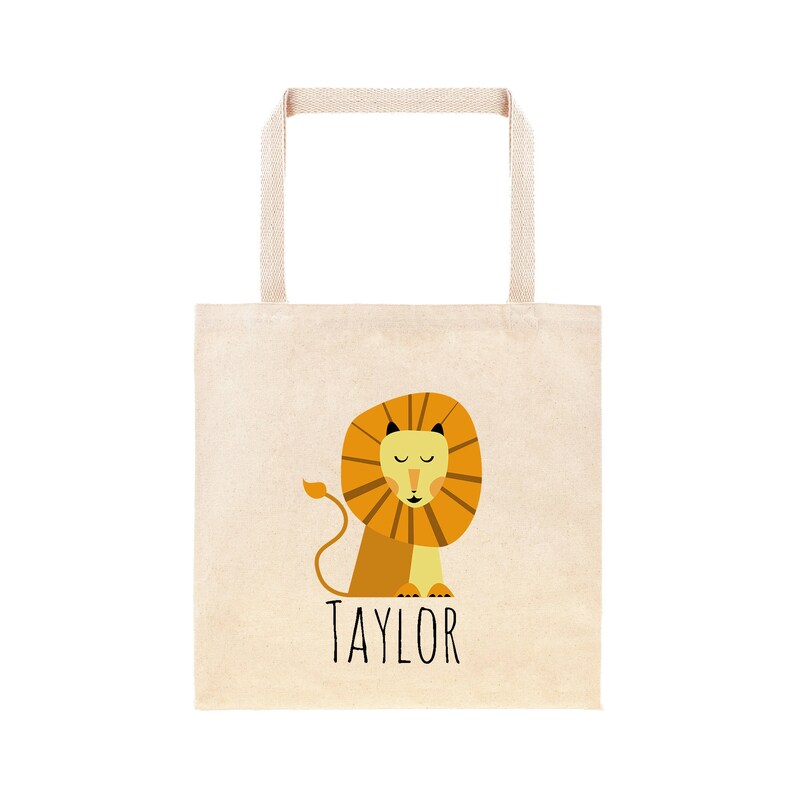 May include: A beige tote bag with a lion illustration and the name "TAYLOR" printed in black.