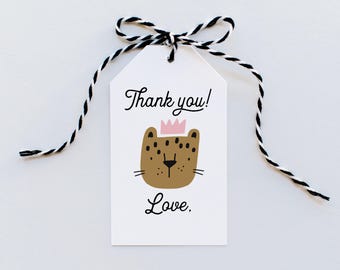 Könnte beinhalten: Ein weißes Geschenk-Etikett mit einer schwarz-weißen Schnurschleife. Das Etikett zeigt ein Cartoon-Leoparden-Gesicht mit einer rosa Krone und den Worten "Thank you! Love."