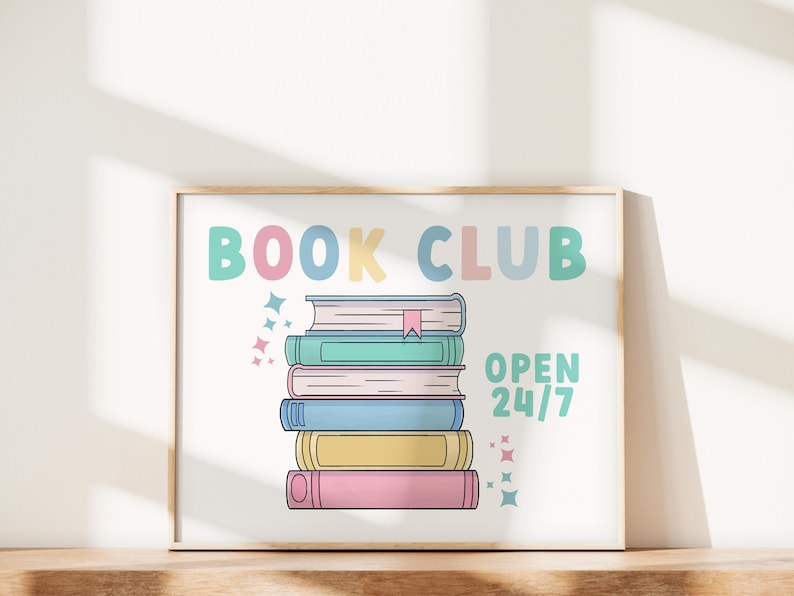 K&ouml;nnte beinhalten: Ein wei&szlig;er gerahmter Poster mit dem Text "BOOK CLUB" in bunten Buchstaben. In der Mitte des Posters ist ein Stapel von f&uuml;nf B&uuml;chern abgebildet. Der Text "OPEN 24/7" befindet sich unter den B&uuml;chern.