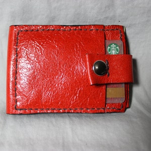 Cartera fina de piel roja de dos pliegues con cierre a presión.