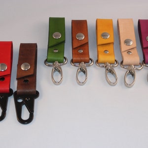 May include: Ten leather keychains with metal swivel clips in various colors, including green, brown, yellow, beige, burgundy, and black.