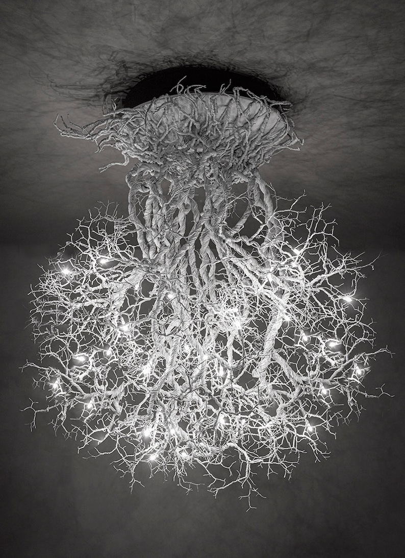 Pu&ograve; includere: Un lampadario bianco a forma di ramo con un grande design rotondo e traforato. Il lampadario &egrave; illuminato da piccole luci bianche.