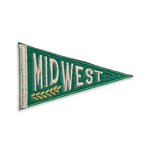 May include: A triangular pennant patch featuring a dark green felt background with a white vertical stripe on the left side. The word MIDWEST is embroidered in white capital letters across the center, accompanied by a small yellow wheat stalk.