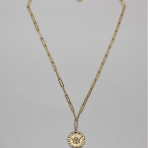 May include: A gold chain necklace with a round pendant featuring an angel design.