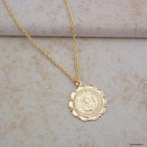 May include: Gold chain necklace with a round pendant featuring a depiction of Saint Christopher. The pendant has a scalloped edge and the words "Saint Christopher" are inscribed around the image.