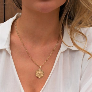 May include: A gold chain necklace with a round pendant featuring an angel design.