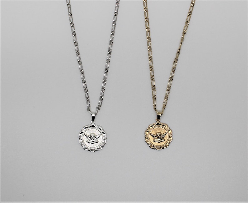 May include: Two silver and gold necklaces with angel pendant charms. The pendants are round and feature a detailed angel design. The chains are both silver and gold.