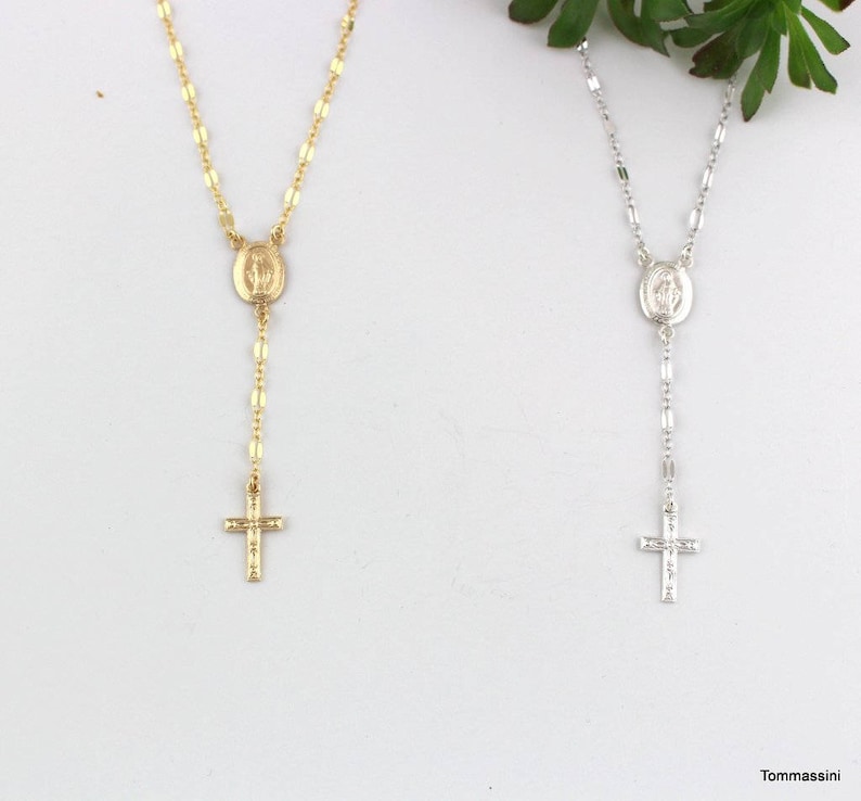 gold and silver chain rosary necklaces with a cross and a small oval mari  pendant. The pendant has a raised image of the Virgin Mary.
