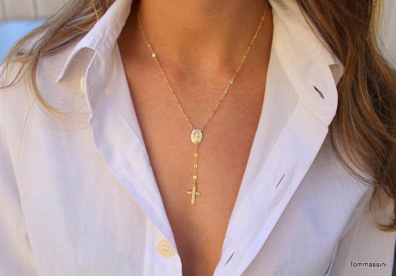 A gold chain Rsary  necklace with a small oval mary pendant and a small cross pendant.