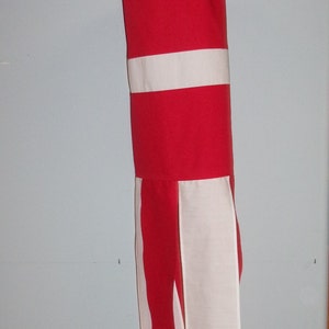 Könnte beinhalten: Ein roter und weißer Windsock mit einem weißen Streifen in der Mitte und weißen Streifen an den Seiten.