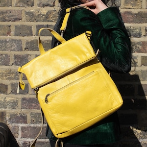 Peut inclure: Un sac à dos en cuir jaune vif doté d'un rabat supérieur avec un compartiment zippé horizontal, une poche frontale zippée secondaire, une poignée de transport supérieure et des bretelles réglables avec des attaches en métal.