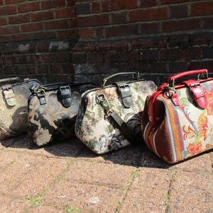 May include: Four vintage-style doctor bags in different colors and patterns. The bags have a brown leather handle and a brass clasp. The bags are lined up in a row on a brick surface.