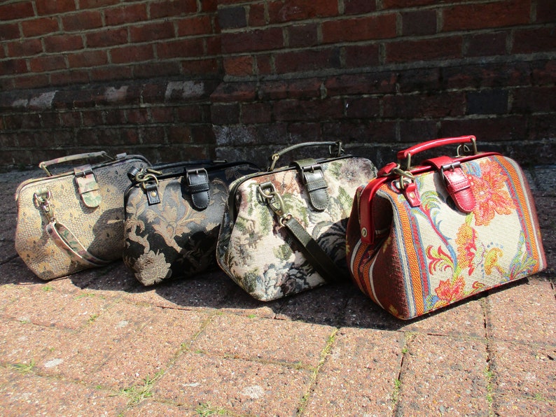 May include: Four vintage-style doctor bags in different colors and patterns. The bags have a brown leather handle and a brass clasp. The bags are lined up in a row on a brick surface.