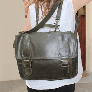 Peut inclure: Un sac à dos en cuir vert foncé avec deux grandes boucles et une sangle. Le sac a un rabat qui se ferme avec une boucle.