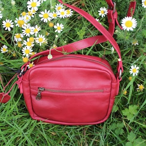 May include: A red leather crossbody bag with a zippered pocket and a brown leather tag that says "Catch"