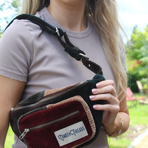 May include: A brown, green and red corduroy fanny pack with a zip closure and the text "CAMDEN THREADS" on the front.