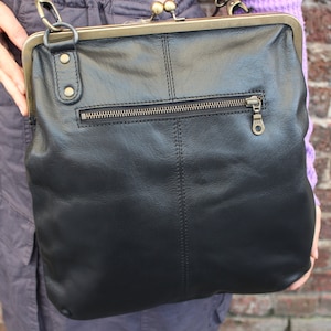 Puede incluir: Bolso bandolera de cuero negro con cierre de marco de latón y un bolsillo con cremallera en la parte posterior.