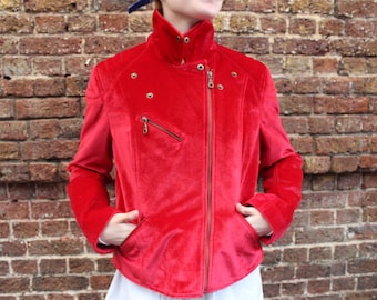 May include: A red velvet moto jacket with a zipper closure and decorative studs. The jacket has a high collar and a cropped length.