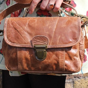 Bolso de cuero desgastado color canela con múltiples compartimentos, estilo mini-satchel moderno, múltiples compartimentos, sección trasera con cremallera, bolsillos laterales centrales con cremallera