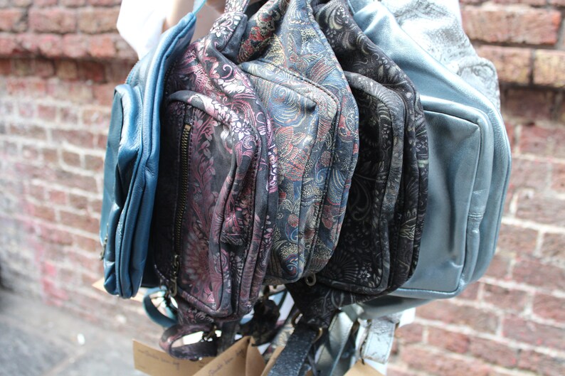Puede incluir: Una colecci&oacute;n de cinco bolsos de diferentes patrones y colores s&oacute;lidos. Los bolsos est&aacute;n hechos de cuero y tienen una variedad de cierres, incluyendo cremalleras y hebillas. Los bolsos son todos en tonos de azul y negro.