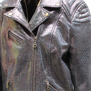May include: A silver metallic leather jacket with a zipper closure and a textured pattern. The jacket has a stand-up collar and a zippered pocket on the left side.