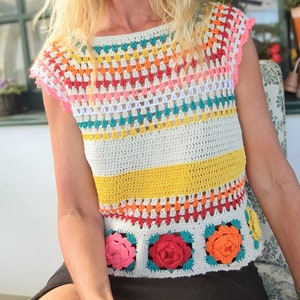 Peut inclure: Un haut crocheté à la main, aux couleurs vives et au motif floral. Le haut présente un mélange de couleurs vives, dont le blanc, le jaune, le rose, l'orange et le turquoise. Le bas du haut est orné d'applications florales carrées.